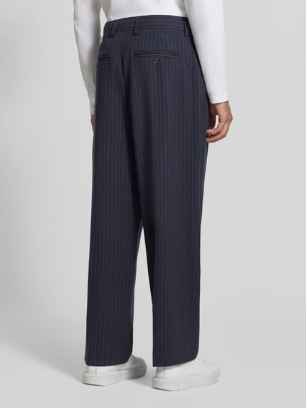 Männermodel trägt Stoffhose mit Bügelfalte Modell 'GRANT' von Casual Friday, dunkelblau mit feinen Streifen, Ganzkörperansicht Rückansicht. Material-Mix mit Viskose-Anteil, Straight Fit, Knopf- und Reißverschluss, französische Eingrifftaschen, Gesäßleistentaschen, Bundweite 43 cm, Innenbeinlänge 75 cm.