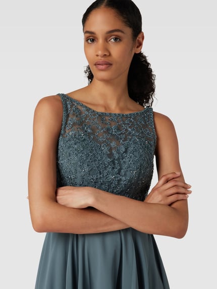 Frauenmodel trägt Regular fit Minikleid mit floralem Spitzenbesatz von Laona in Blau mit semitransparenter Optik und Ziersteinbesatz, Nahaufnahme Oberkörper.