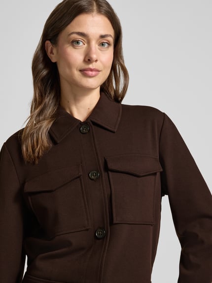Vrouwenmodel draagt Regular Fit Hemdjacke mit Viskose-Anteil van s.Oliver RED LABEL in donkerbruin met grote zakken, gladde textuur, Nahaufnahme bovenlichaam.