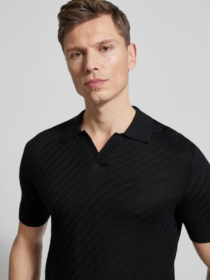 Männermodel trägt schwarzes Slim Fit Poloshirt mit Lyocell-Anteil von Emporio Armani, Strick-Optik, Nahaufnahme Oberkörper.