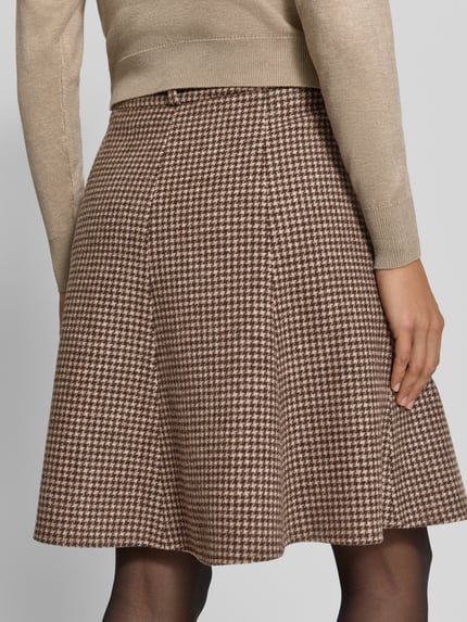 Frauenmodel trägt Ausgestellter Mini-Rock aus reiner Wolle von GANT, braunes Hahnentrittmuster, strukturierte Oberfläche, Ganzkörperansicht Rückansicht.