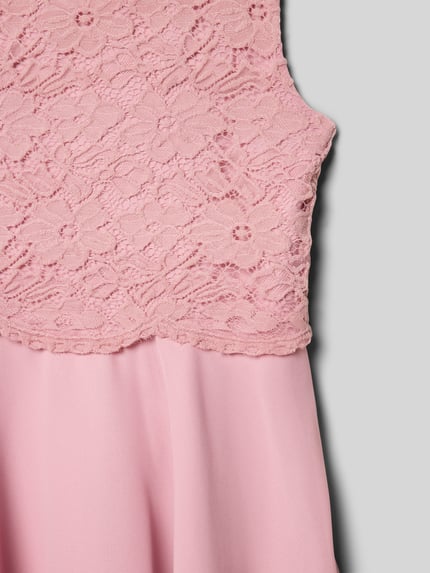 Mädchen trägt Knielanges Kleid mit Rundhalsausschnitt von Happy Girls, taliowany krój, długość do kolan, wszyty zamek błyskawiczny, okrągły dekolt, rozkloszowana spódnica, długość tyłu 73 cm w rozmiarze 140, jasnoróżowa koronka i gładka tkanina, detailaufnahme.