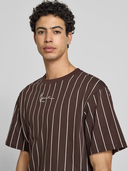 Männermodel trägt Regular Fit T-shirt mit logostitching van KARL KANI aus puur katoen, bruin met witte strepen, nahaufnahme oberkörper.