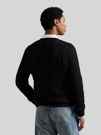 Männermodel trägt Regular Fit Strickpullover aus reiner Baumwolle von Polo Ralph Lauren in Schwarz, Zopfmuster, Rückansicht Ganzkörperansicht.