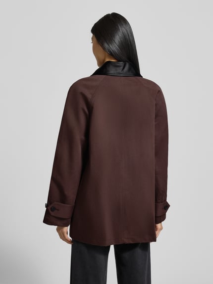 Kobiece model prezentuje Trenchcoat mit Umlegekragen und verdeckter Knopfleiste od Staud w kolorze brązowym, widok całej sylwetki z tyłu. Relaxed Fit, bawełniany miks.