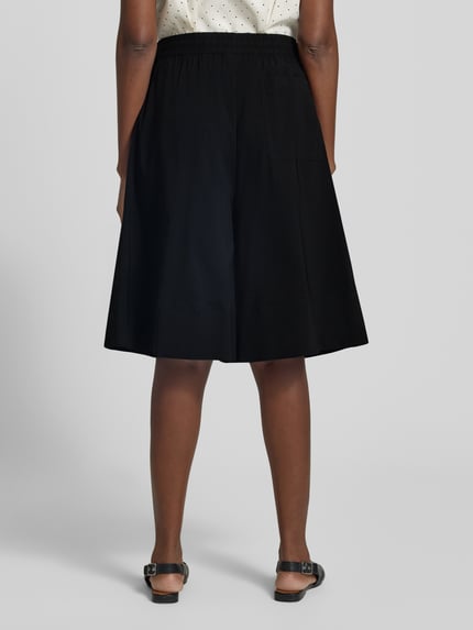 Vrouwenmodel draagt Bermudas met wijde pijpen model 'Jules' van FREE/QUENT, zwarte viscosemix met stretch, elastische tailleband, binnenbeenlengte 30 cm, taillewijdte 38 cm, volledige achteraanzicht.
