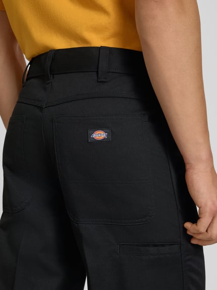 Männermodel trägt Loose Straight Fit Hose mit Bügelfalten von Dickies, Material-Mix mit Baumwoll-Anteil, Detailaufnahme Rückansicht.