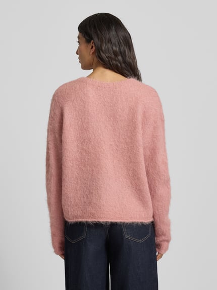 Männermodel trägt Strickpullover mit gerippten Abschlüssen Modell 'NUNY' von American Vintage, luźny krój, różowy, tekstura puszysta, widok całej sylwetki z tyłu.