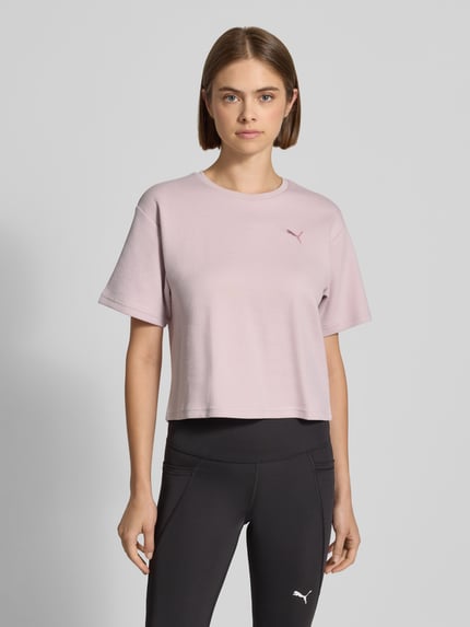 Kobiece modelka nosi Relaxed Fit T-Shirt aus Häkelspitze od PUMA, jasnoróżowy kolor, prosta forma, damski t-shirt, Ganzkörperansicht von vorne.