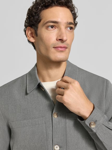 Männermodel trägt Hybrid Jacke mit Brusttaschen Modell 'Marseille' von Les Deux aus grauem Material-Mix, Nahaufnahme Oberkörper.
