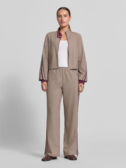 Vrouwenmodel draagt Wide Fit broek met viscose van Liu Jo, elastische materiaalmix, logodetail, tunnelkoord, steekzakken, bandwijdte maat S 38 cm, binnenbeenlengte 80 cm, rustig bruin met paarse accenten, ganzicht voorkant.