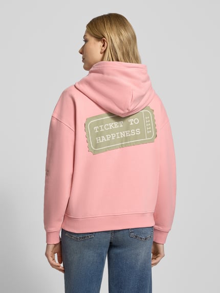 Frauenmodel trägt Oversized Sweatjacke mit Kapuze von Smith and Soul in Rosa mit großem Ticket-Print, Baumwoll-Mix, Rückansicht.