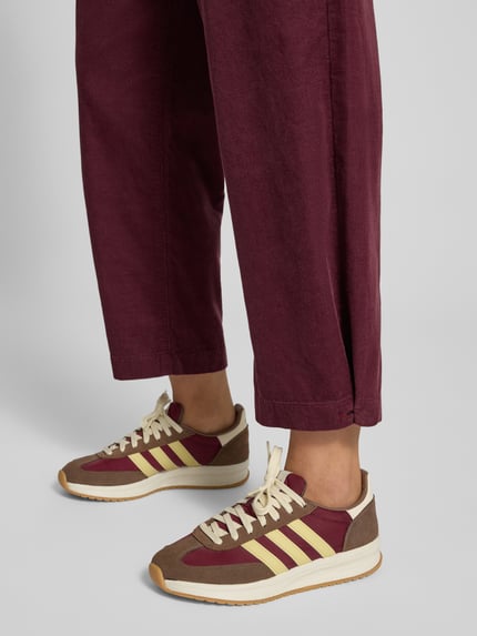 Mädchen trägt Loose Fit Cordhose aus reiner Baumwolle von Marc O'Polo DENIM, bordeauxrot, strukturierte Oberfläche, Nahaufnahme Beinbereich