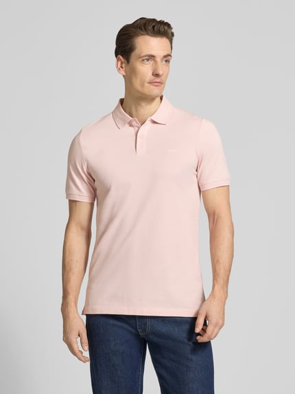 Männermodel trägt Regular Fit Poloshirt aus reiner Baumwolle von s.Oliver RED LABEL in Hellrosa, unifarben, Ganzkörperansicht von vorne.