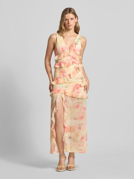 Vrouwenmodel draagt maxi-jurk met ruches van Gina Tricot, nauwsluitend, bloemenprint, V-hals, mouwloos design, loopsplit, all-over print. Ganzkörperansicht van voren.