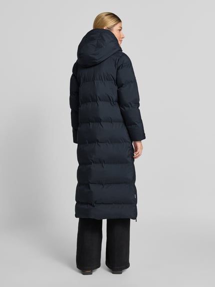 Frauenmodel trägt Steppmantel mit Reißverschlusstaschen Modell 'MAYLA4' von khujo, dunkel, wattiert, glatte Textur, Ganzkörperansicht Rückansicht.