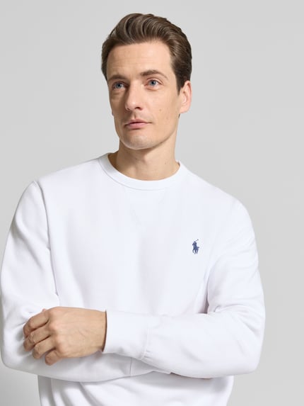 Männermodel trägt Regular Fit Sweatshirt aus Baumwoll-Mix von Polo Ralph Lauren in Weiß mit Logo-Detail, Nahaufnahme Oberkörper.