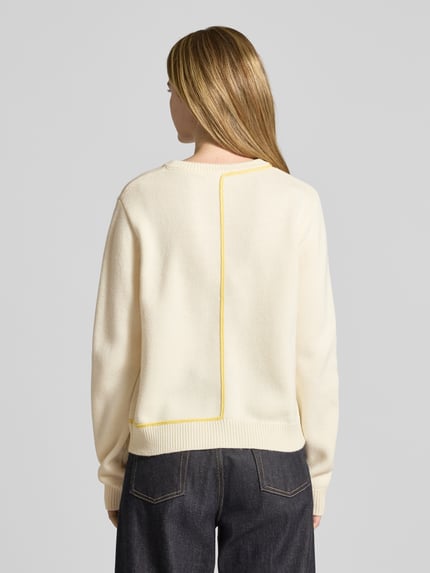 Frauenmodel trägt Relaxed Fit Strickpullover mit Woll-Anteil Modell 'JANIQUE' von Guido Maria Kretschmer WOMAN im Material-Mix, Rundhalsausschnitt, Rückenlänge 57 cm, cremefarbener Stoff mit gelber Kontrastnaht, strukturierte Oberfläche, Ganzkörperansicht Rückansicht.