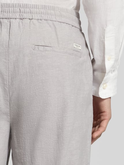Männermodel trägt Jogpants aus Baumwoll-Leinen-Mix Modell 'WARREN' von Scotch & Soda, hellgrau, elastischer Bund, Detailaufnahme, Regular-Fit, Bundweite 41 cm, Innenbeinlänge 75 cm bei Größe 32/32.