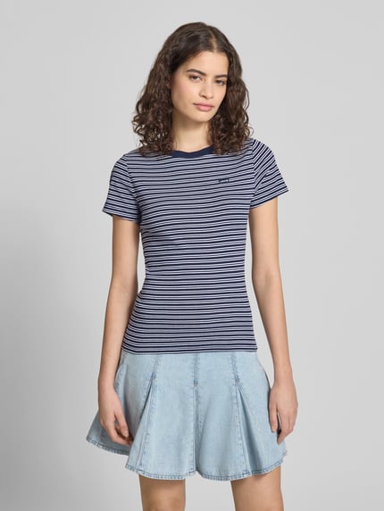 Frauenmodel trägt Slim Fit T-Shirt aus reiner Baumwolle von Levi's®, gestreift mit Allover-Muster und Label Patch, Ganzkörperansicht von vorne.