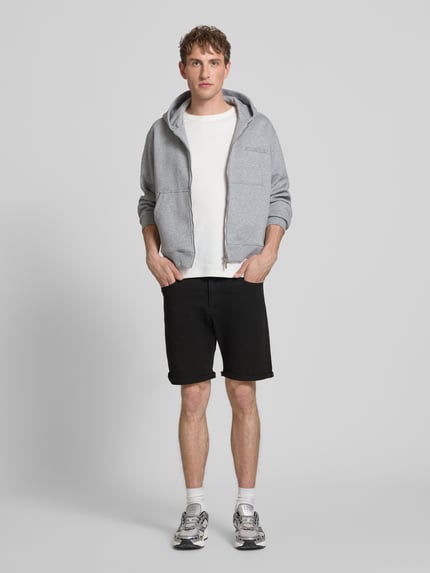 Männermodel trägt schwarze Jeansshorts mit Umschlag und Eingrifftaschen Modell 'RICK ALLEN' von Jack & Jones, Regular Fit, aus Baumwoll-Elasthan-Mix, Bundweite 43 cm, Innenbeinlänge 20 cm, Ganzkörperansicht von vorne
