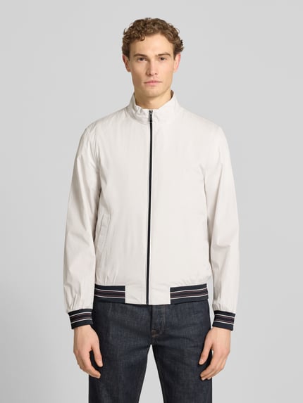 Männermodel trägt blouson met opstaande kraag en ritssluiting van Geox, regular fit, steekzakken, wit, ganzkörperansicht van voren. Ruglengte bij maat M 68 cm, schouderbreedte 46 cm, borstwijdte 56 cm, mouwlengte 68 cm.