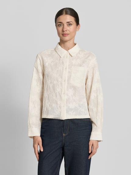 Frauenmodel trägt Bluse mit Brusttaschen Modell 'Sylvia' von MSCH Copenhagen in Creme mit Knopfleiste und floralem Embroidery Design, Ganzkörperansicht von vorne.