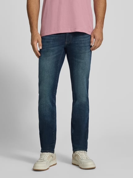 Männermodel trägt Modern Fit Jeans aus Baumwoll-Mix Modell 'Chuck' von Brax in Denim-Optik, 5-Pocket-Design, Ganzkörperansicht von vorne.