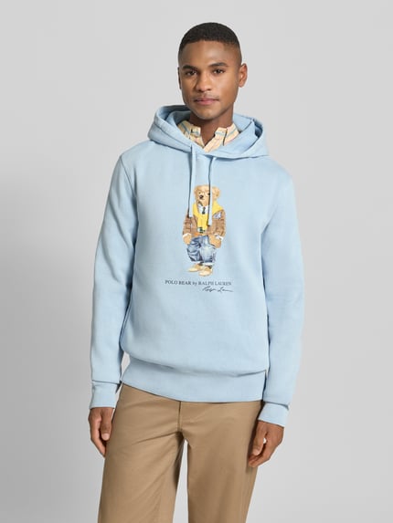Männermodel trägt Hoodie mit Kapuze von Polo Ralph Lauren aus Baumwoll-Mix, Label-Print, lockerem Schnitt, gerippte Abschlüsse, Ganzkörperansicht von vorne.