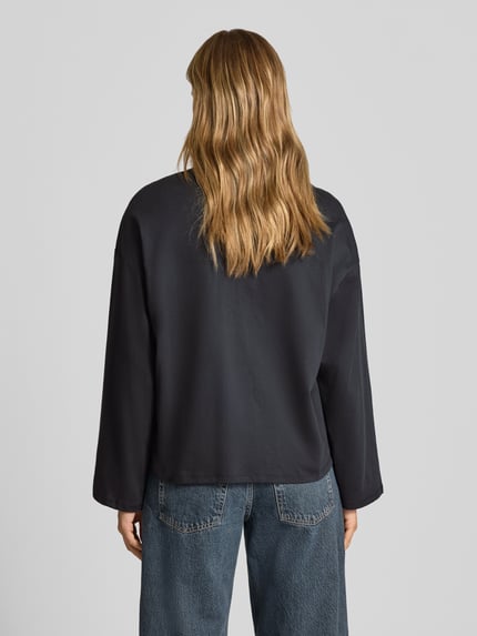 Frauenmodel trägt Oversized Langarmshirt aus reiner Baumwolle von REVIEW, lockere Passform, dunkel, glatte Textur, Ganzkörperansicht Rückansicht