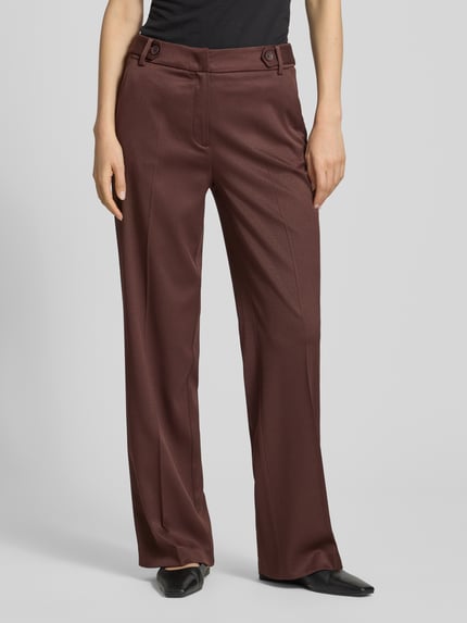 Frauenmodel trägt Wide Fit Stoffhose mit Viskose-Anteil von More & More in Braun mit Bügelfalten, Strukturmuster und Haken-Reißverschluss, Elastischer-Material-Mix, Bundweite 37 cm, Innenbeinlänge 80 cm, Ganzkörperansicht von vorne.
