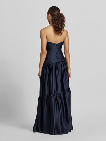 Kobiece modelka nosi 'Abendkleid im Stufen-Look' od Luxuar, długa sukienka, krój bez rękawów, efekt stopniowania, taliowany krój, zamek błyskawiczny z tyłu, długość tyłu w rozmiarze 36: 125 cm, szerokość klatki piersiowej w rozmiarze 36: 34 cm, granatowy połysk, gładka tekstura, pełen widok sylwetki od tyłu