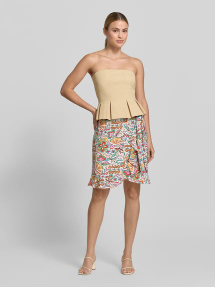Frauenmodel trägt Wickelrock aus Viskose-Mix im Allover-Look von Christian Berg Woman, mehrfarbig, A-Linie, Minirock, Ganzkörperansicht von vorne.