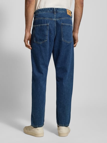 Männermodel trägt Tapered Fit Jeans aus reine katoen Modell 'RUNNA' van Marc O'Polo Denim, denim look, 5-pocket, label patch, Ganzkörperansicht Rückansicht.