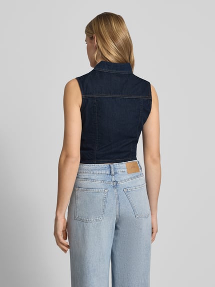 Vrouwenmodel draagt Cropped Jeansbluse mit Label-Patch van Guess Jeans in donkerblauw, puur katoen, nauwsluitend model, kentkraag, knoopsluiting, labelpatch, ruglengte bij maat S 43 cm, geheel achteraanzicht.