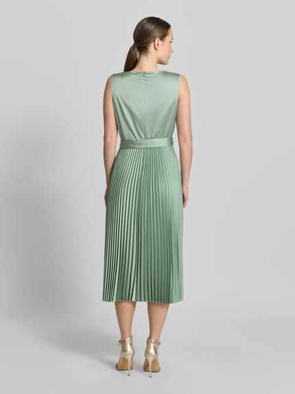 Frauenmodel trägt Midikleid mit Plisseefalten und Bindegürtel von comma in zartem Mintgrün, Material-Mix, A-Linie, Ganzkörperansicht Rückansicht.