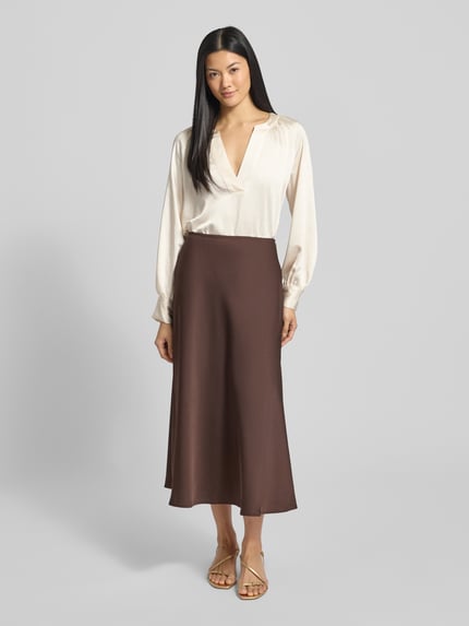 Frauenmodel trägt Oversized Blusentop mit Cacharel-Falte von s.Oliver RED LABEL, Optik: Unifarben, Passform: Oversized, Ausschnitt: Tiefer V-Ausschnitt, Ärmelform: Langarm, Ärmelabschluss: Manschette, Rumpfabschluss: abgerundet, Ganzkörperansicht von vorne.