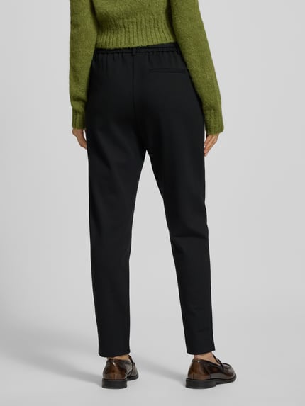Frauenmodel trägt schwarze Stoffhose in verkürzter Passform Modell 'Popye' von MSCH Copenhagen, lockerer Schnitt, Ganzkörperansicht Rückansicht.