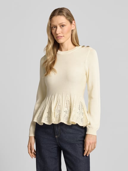 Frauenmodel trägt Strickshirt mit Schößchen Modell 'UTAMA' von Bash, Baumwoll-Modal-Mix, Zierknöpfe, Lochmuster, Körpernaher-Schnitt, Rundhalsausschnitt, gerippte Ärmelabschlüsse, in Creme, Ganzkörperansicht von vorne.