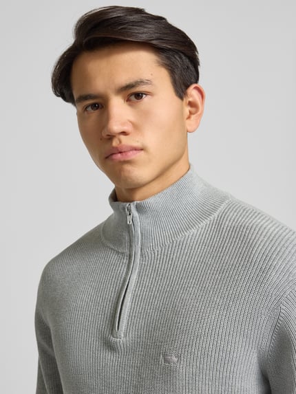 Männermodel trägt Strickpullover mit Stehkragen von Levi's®, graue Farbe, gerippte Struktur, kurzer Reißverschluss, Label-Stitching, Nahaufnahme Oberkörper.
