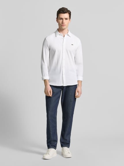 Männermodel trägt Slim Fit Freizeithemd aus reiner Baumwolle von Lacoste, Optik: Unifarben, langarm, Kentkragen, Piqué, Ganzkörperansicht von vorne.