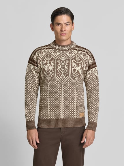 Männermodel trägt Strickpullover mit Stehkragen von Dale of Norway in Braun mit Muster, gerader Schnitt, Label-Patch, Ganzkörperansicht von vorne.