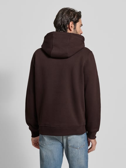 Männermodel trägt Regular Fit Hoodie aus Baumwoll-Mix von Tommy Hilfiger in Optik: Unifarben mit geripptem Rumpfabschluss, Ganzkörperansicht Rückansicht.