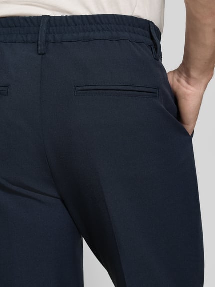 Männermodel trägt Hose mit elastischem Bund und Bügelfalten Modell 'MARC 2.0' von Casual Friday, Detailaufnahme Rückansicht. Material-Mix mit Viskose-Anteil, Regular Fit, Eingrifftaschen und Paspeltaschen am Gesäß.
