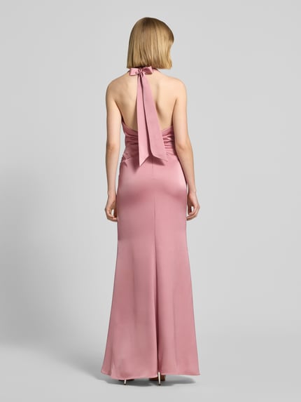 Modelka kobieca ma na sobie Abendkleid mit tiefem Rückenausschnitt und Neckholder od Mascara, różowy satynowy materiał, dopasowany krój, długość maxi, wodospadowy dekolt, zapięcie na szyi na haczyk, marszczenia, głęboki dekolt na plecach, zapięcie z tyłu na haczyk i zamek, długość pleców w rozmiarze 36: 136 cm, szerokość w rozmiarze 36: 41 cm, widok całej sylwetki od tyłu.