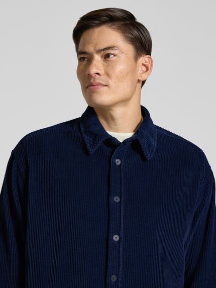 Männermodel trägt Regular Fit Freizeithemd aus Cord Modell 'PADOW' von American Vintage in Dunkelblau, Knopfleiste, Nahaufnahme Oberkörper, reine Baumwolle, Kentkragen, KI-modifiziertes Bild.
