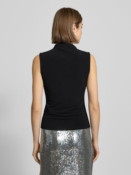 Vrouwenmodel draagt Shaped Fit Shirt zonder mouwen Model 'MADISON' van Pieces in effen zwart met labelstitching, hooggesloten hals, rugaanzicht.