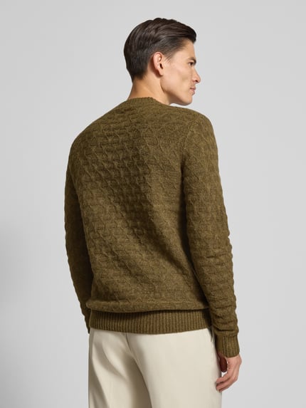 Męski model nosi Strickpullover mit gerippten Abschlüssen Modell 'BLASIMON' od Jack & Jones Premium, oliwkowy, melanż, widok całej sylwetki z tyłu. Regularny krój, dzianina z domieszką wełny, ściągacze, długość tyłu 71 cm, rękawy 72 cm.