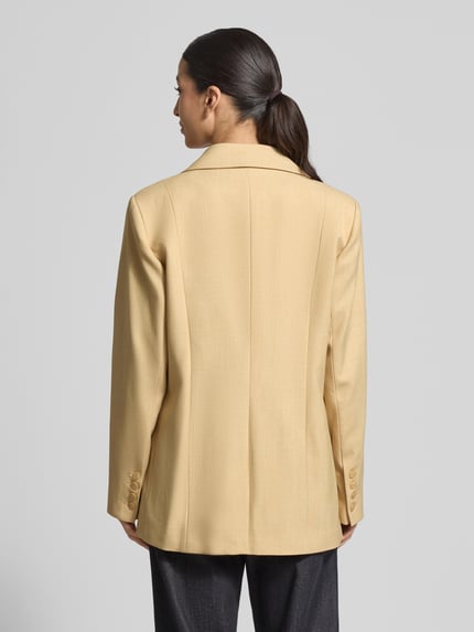 Vrouwenmodel draagt Regular Fit Blazer met viscose-aandeel model 'stacy' van Gestuz, beige, reverskraag, rugaanzicht, context: dames blazer, materiaal-mix met viscose-aandeel, regular fit, model 'stacy', reverskraag, knoopsluiting, klepzakken, ruglengte bij maat 36: 74 cm, borstwijdte bij maat 36: 52 cm, mouwlengte bij maat 36: 64 cm. Ganzlichaansicht achteraan.