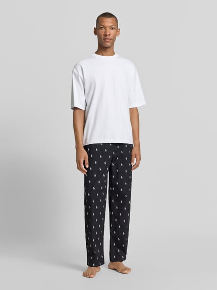 Männermodel trägt schwarze Regular Fit Pyjama-Hose aus reiner Baumwolle von Polo Ralph Lauren Underwear mit weißem Print, Ganzkörperansicht von vorne.
